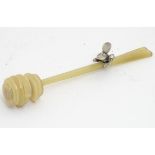 A celluloid honey drizzler / dipper with a silver honey bee decoration to handle, 6” long.