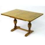 A late 20thC oak dining table with a rectangular table top and draw leaf to each end,