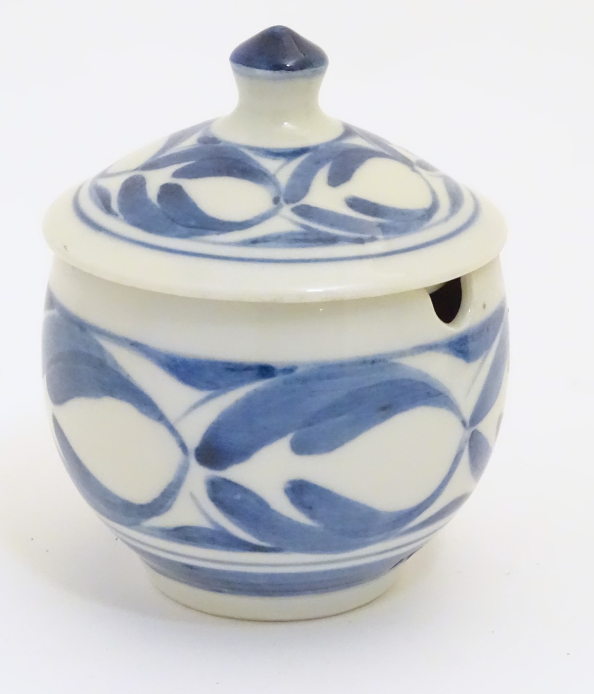 A Derek Emms studio pottery lidded preserve pot, with blue and white stylised foliage decoration.