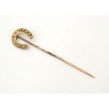A Victorian 9ct gold stick pin surmounted by a horseshoe.