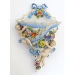 A German porcelain wall pocket decorated with two cherubs / putti and flowers in relief.