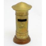 A money box in the form of a brass pillar post box on a turned wooden base and removable domed top,