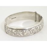 A silver bangle bracelet with engraved decoration.