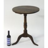 A late 18thC oak tripod table with a circular table top above a turned stem and standing on three
