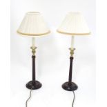 A pair of 21stC table lamps formed as columns with turned and fluted wooden bases,