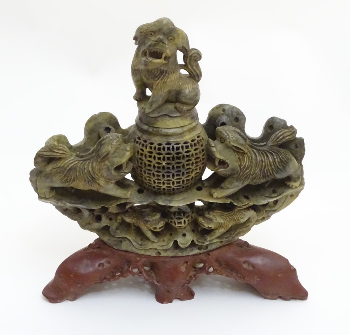 A 19thC Asian carved soapstone reticulated lidded bowl, flanked by foo dogs,