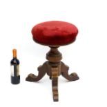 A Victorian walnut adjustable stool, having a turned stem and a triform pedestal base.