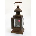 A copper cased, hinged handled oil lamp with bevelled glass panels and red glass section to rear.