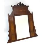 A late 19thC / early 20thC mahogany mirror with carved floral pediment flanked by urn finials.