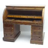 A mid / late 19thC mahogany roll top bureau with a quarter cylindrical weighted top,