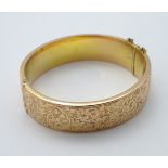 A 9ct gold bangle bracelet with engraved decoration CONDITION: Please Note - we do