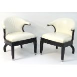 A pair of Art Deco armchairs with white leather upholstery and ebonised wooden frames.