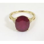 A 10k gold ring set with large red stone flanked by chip set diamonds,