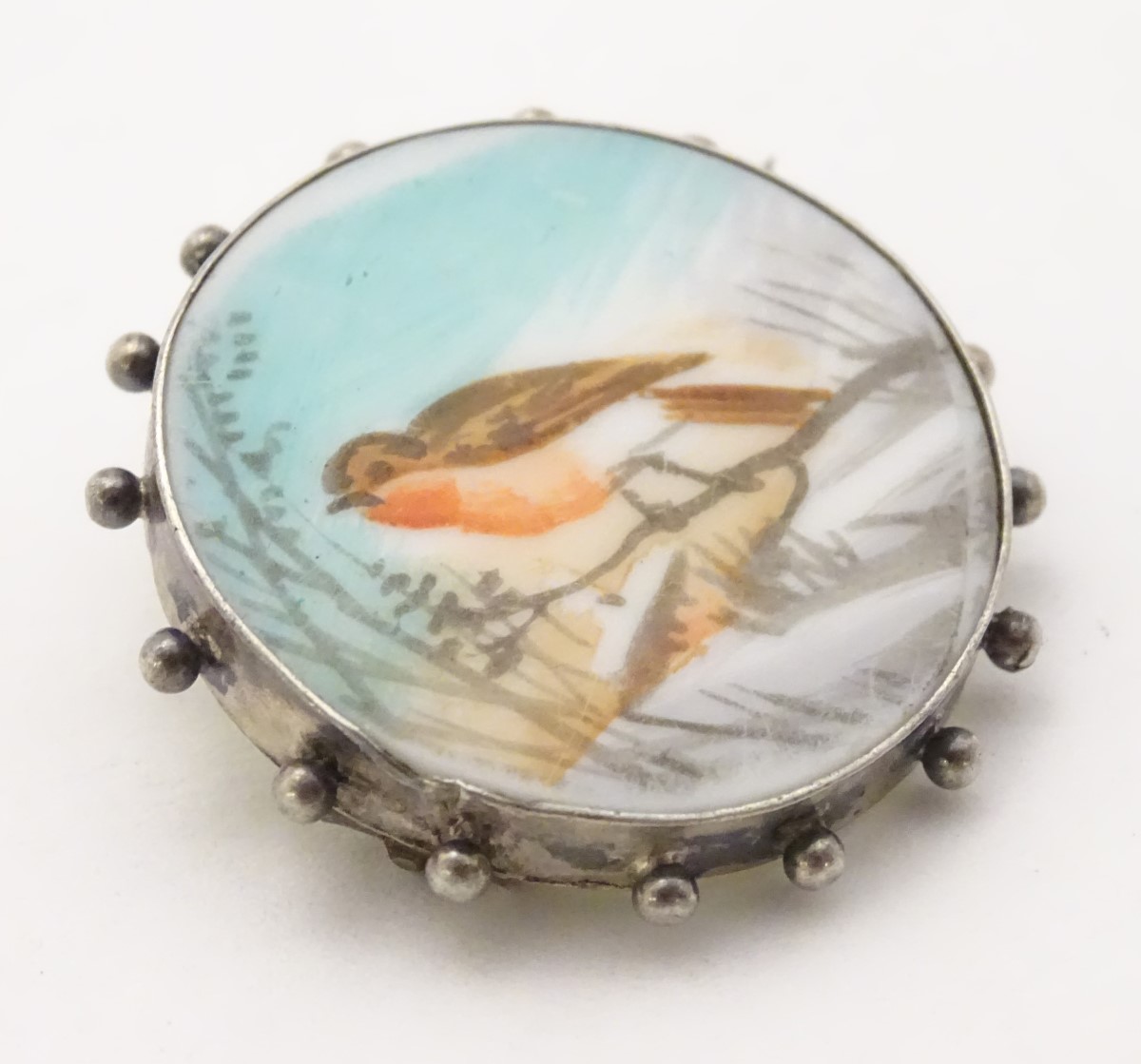 A white metal brooch with hand painted scene to centre depicting a robin in a snowy landscape. - Image 7 of 10