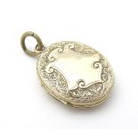 A Victorian yellow metal locket with engraved decoration and cartouche 1 /4" long