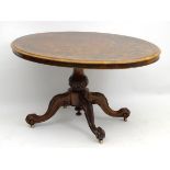 A Victorian burr walnut loo table with an oval tilt top and carved acanthus pedestal base standing