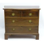 An early 19thC mahogany serpentine fronted chest of drawers comprising 2 short over 2 long drawers,