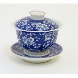 A Chinese blue and white tea bowl, lid and saucer, decorated with cherry blossom.