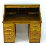 A mid 20thC oak 'Lebus Desk' with a tambour roll top and double pedestal base,