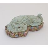 A recumbent Chinese foo dog with a crackle glaze lying on a bed of stylised clouds.