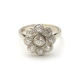 An 18ct white gold ring set with central old cut diamond bordered by 8 further diamonds in a daisy