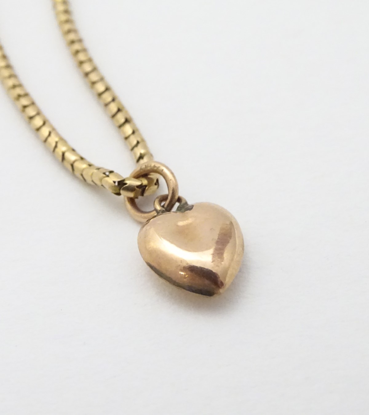 A gold chain (tests as 14ct) with a 9ct gold heart shaped charm / pendant.