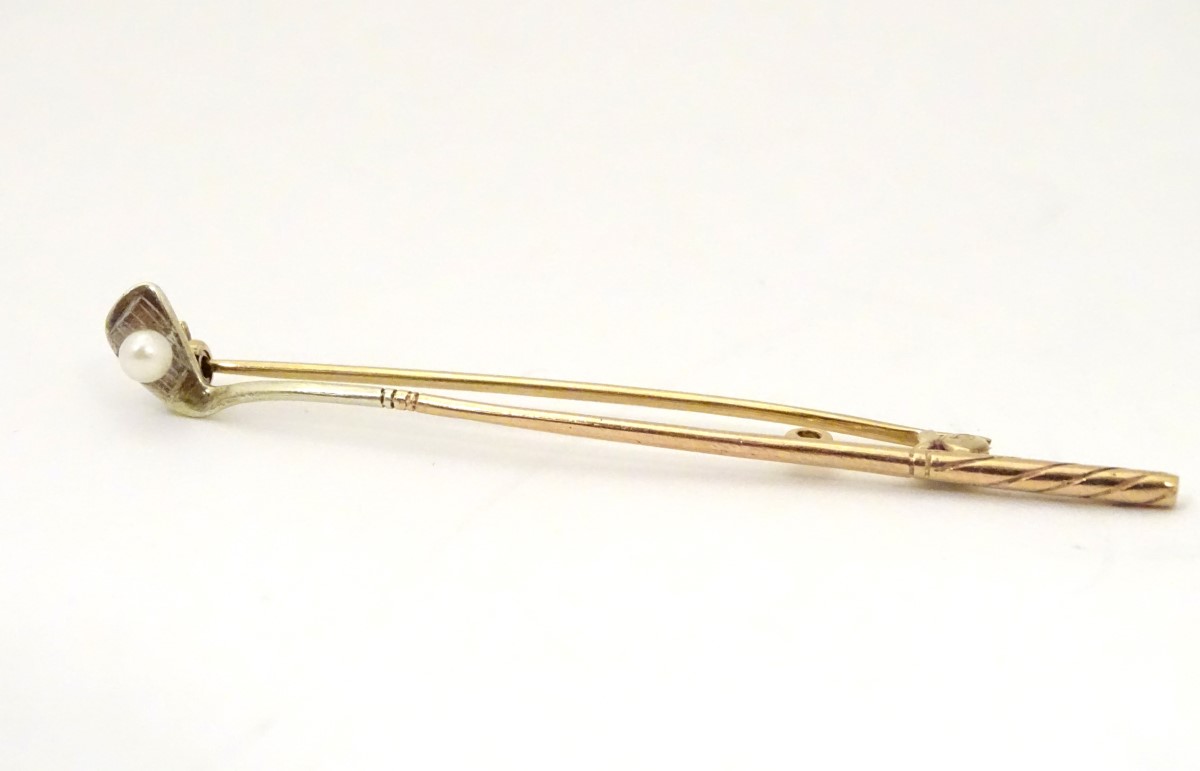 A 9ct gold bar brooch with golf club decoration with seed pearl golf ball detail.