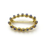 An 18ct gold brooch of oval form set with blue spinel, 1” wide.