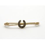 A 9ct gold bar brooch with horseshoe to centre set with seed pearls. 1 ¼” wide.