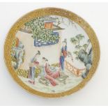 A small Chinese famille rose plate decorated with figures on a terrace within a landscape with a
