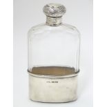 A glass hip flask with silver top and beaker to lower section.