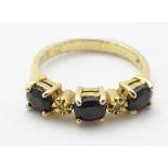 A 9ct gold ring set with three dark garnet stones and chip set diamonds.