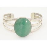 A silver bangle bracelet set with large aventurine cabochon to centre.