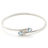 A white metal bangle formed bracelet set with aquamarine heart shaped terminals and marked '9KT