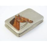 A white metal box with enamel horse head decoration to top.