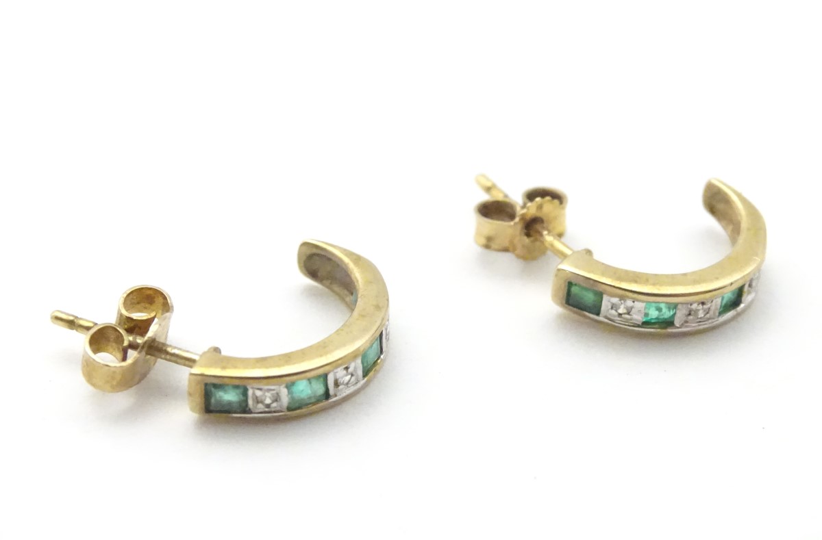A pair of 9ct gold earrings set with diamonds and emeralds.
