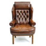 A 21stC leather wingback armchair with a deep buttoned upholstered backrest,