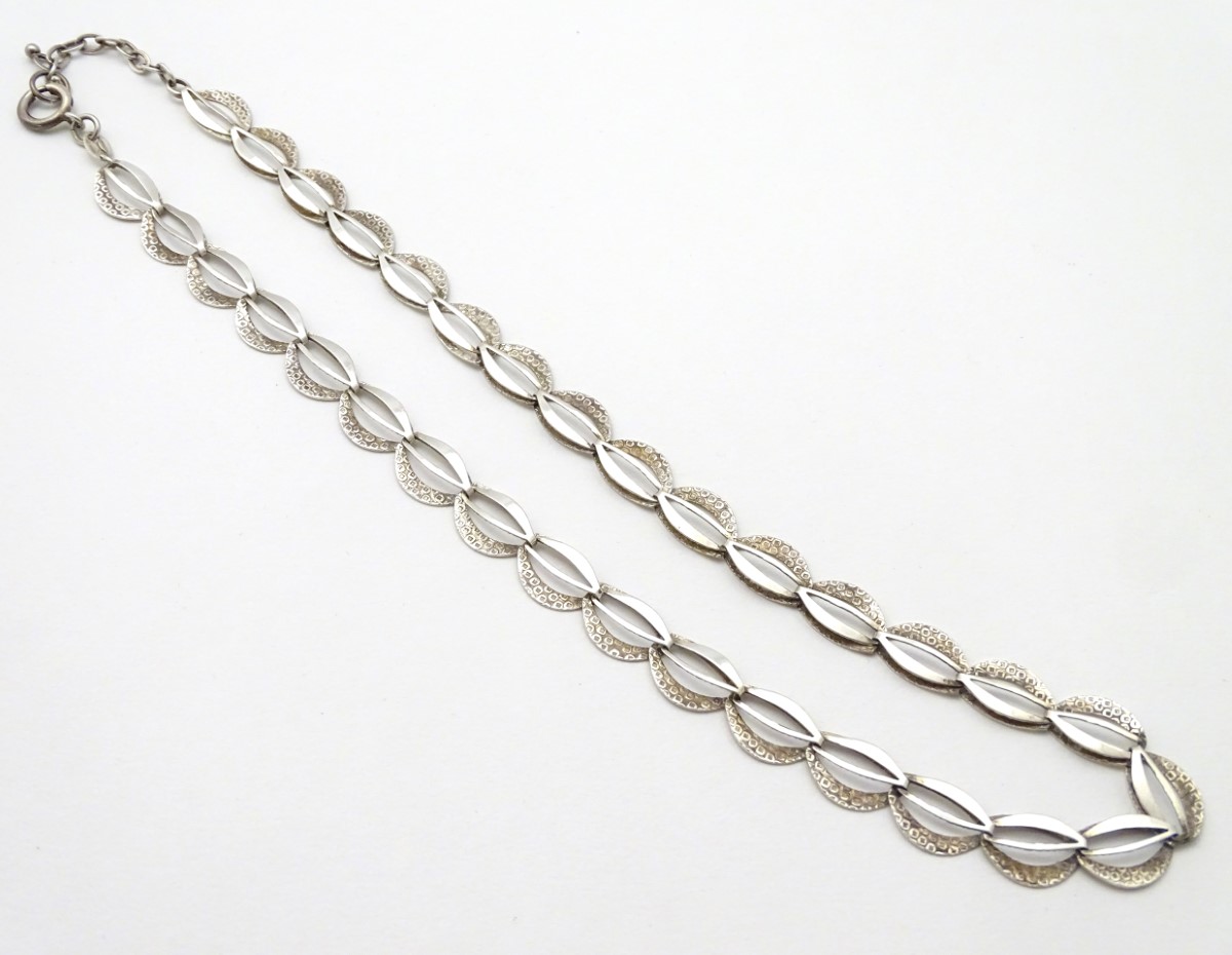 A silver necklace with textured decoration. Approx.