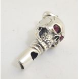A 21stC novelty white metal whistle formed as a skull, having inset red stone eyes,