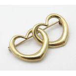 A gold brooch formed as two hearts.