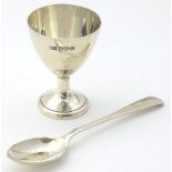 A silver pedestal egg cup together with a spoon.
