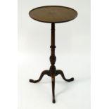 An early 20thC mahogany tripod table with a circular dished top above a tapering turned stem and