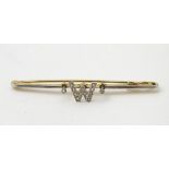 A 15ct gold and platinum bar brooch with diamond set 'W', 2 ¼” wide.