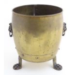 An early-mid 20thC brass coal barrel, with lion's paw handles and standing on three lion's paw feet.