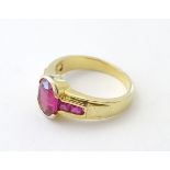 A 10ct gold ring set with central ruby flanked by 2 further rubies to each shoulder.