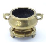 A Chinese twin handled brass pot / censer raised on three feet, with a brass three footed stand.
