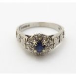 An 18ct white gold ring set with central blue sapphire coloured spinel bordered by diamonds and