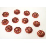 12 French retro buttons with two holes, decorated with colourful chevrons in relief on a red ground.