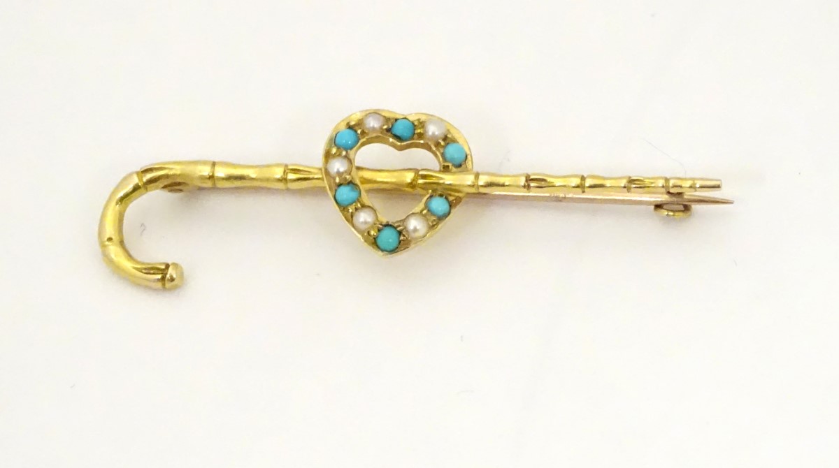 A gold bar brooch/ pin formed as a walking stick / cane with heart decoration set with seed pearl