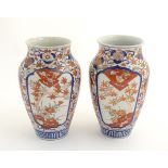 A pair of Imari vases with panelled floral decoration, with stylised trees and flowers. Approx.